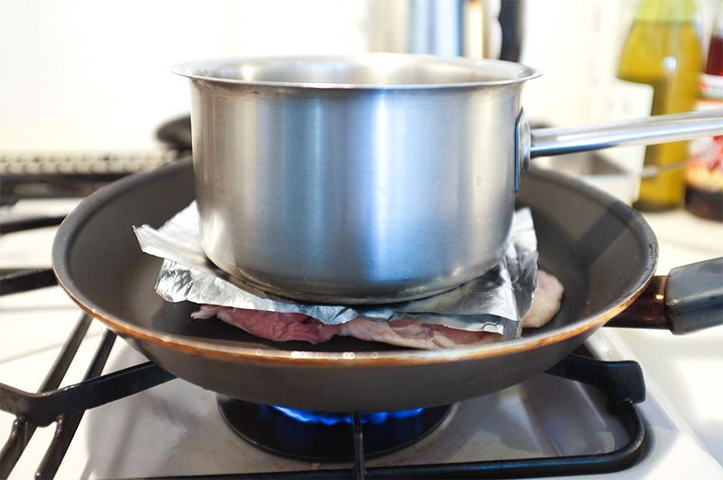 Курку смажать під гнітом, щоб поверхня щільно прилягала до сковороди (фотографія nippon