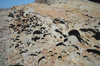 Бухту зліва і справа обрамляють скелі, що нагадують вулканічну лаву, застиглу в химерних формах